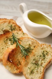 Photo of Tasty baguette with garlic, dill, rosemary and oil on board, closeup