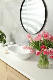 Photo of Vase with beautiful pink tulips near sink in bathroom