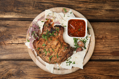 Photo of Delicious grilled pork chop served on wooden table, top view