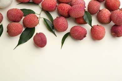 Fresh ripe lychees with leaves on beige background, flat lay. Space for text