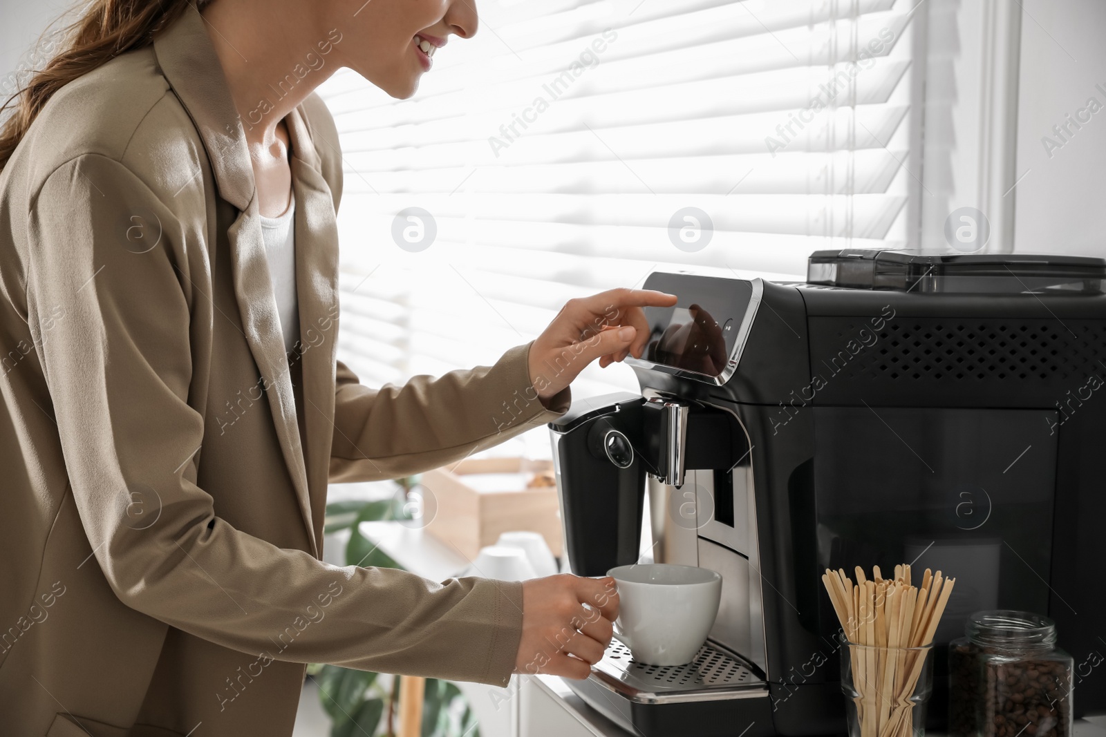 Photo of Young woman preparing fresh aromatic coffee with modern machine in office, closeup