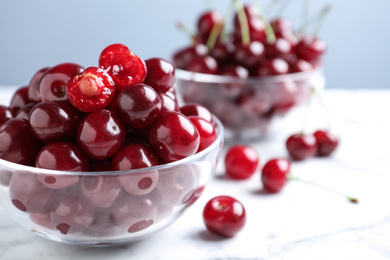 Photo of Sweet juicy cherries on white marble table, closeup