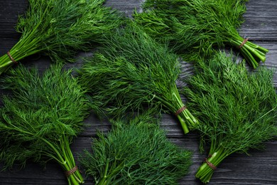 Bunches of fresh dill on black wooden table, flat lay