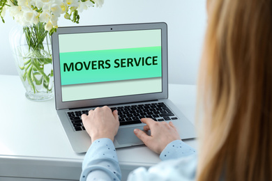 Image of Woman using laptop to order movers service indoors, closeup