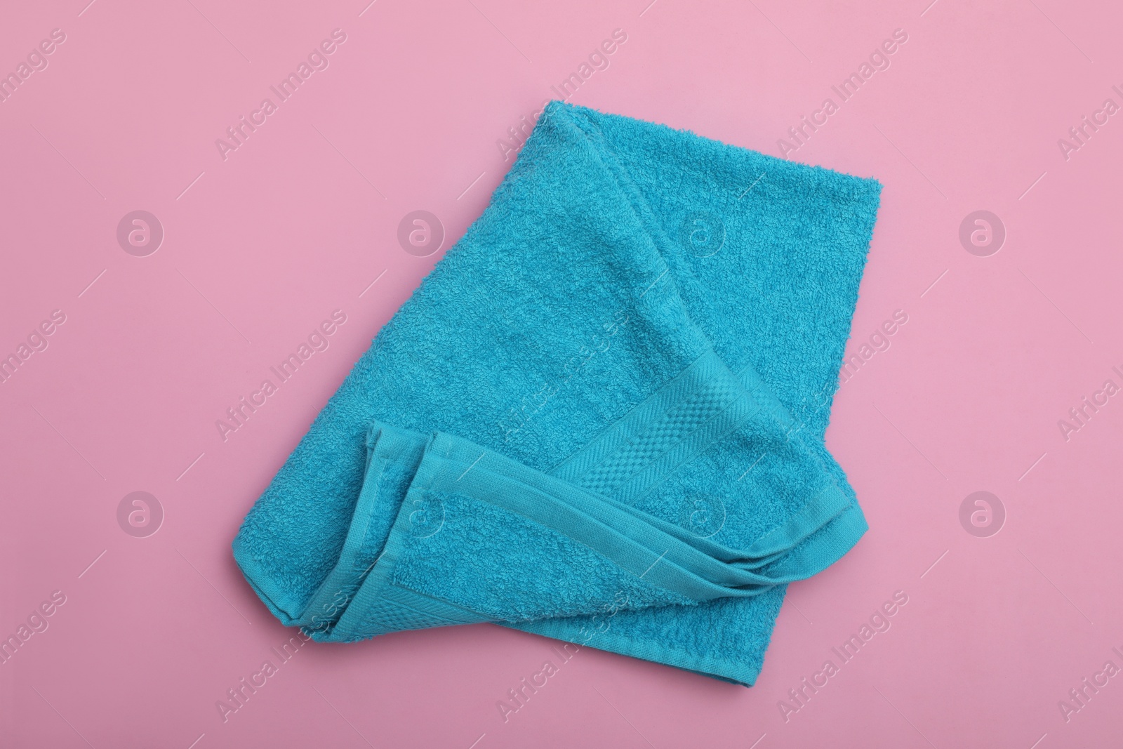 Photo of Folded light blue beach towel on pink background, top view