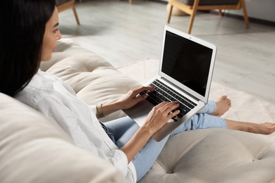 Young woman working with laptop on sofa indoors, closeup