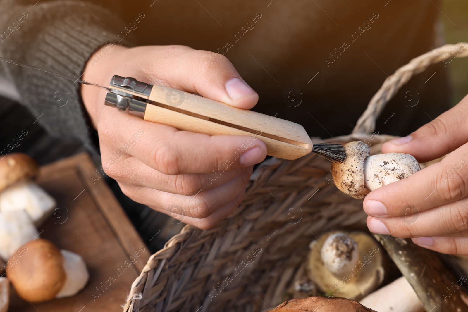 Photo of Man cleaning mushroom with brush on knife, closeup