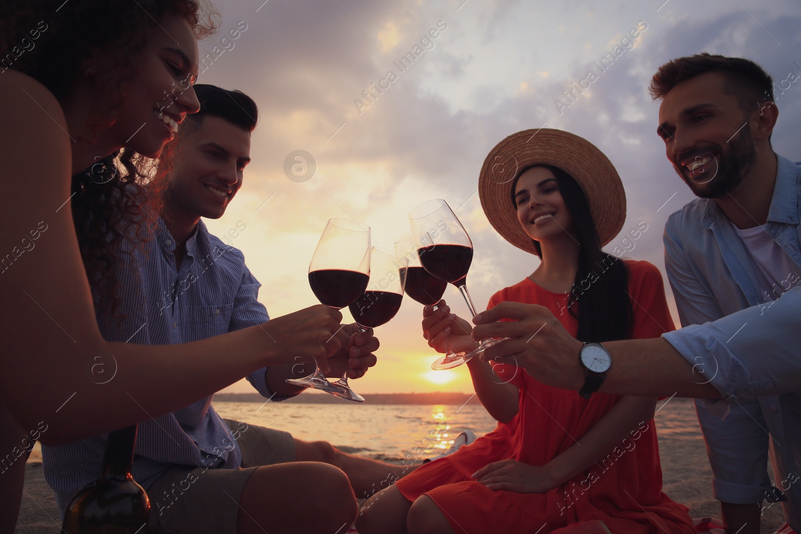 Photo of Group of friends having picnic near river at sunset