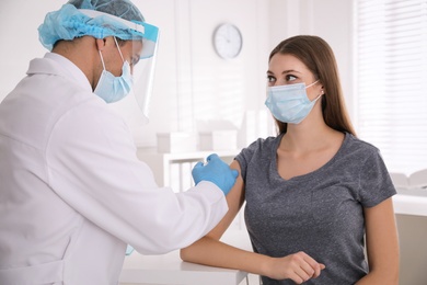 Doctor vaccinating young woman against Covid-19 in clinic