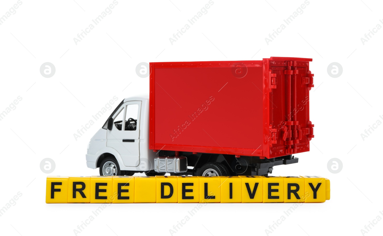 Photo of Toy truck and cubes with words FREE DELIVERY isolated on white. Logistics and wholesale concept