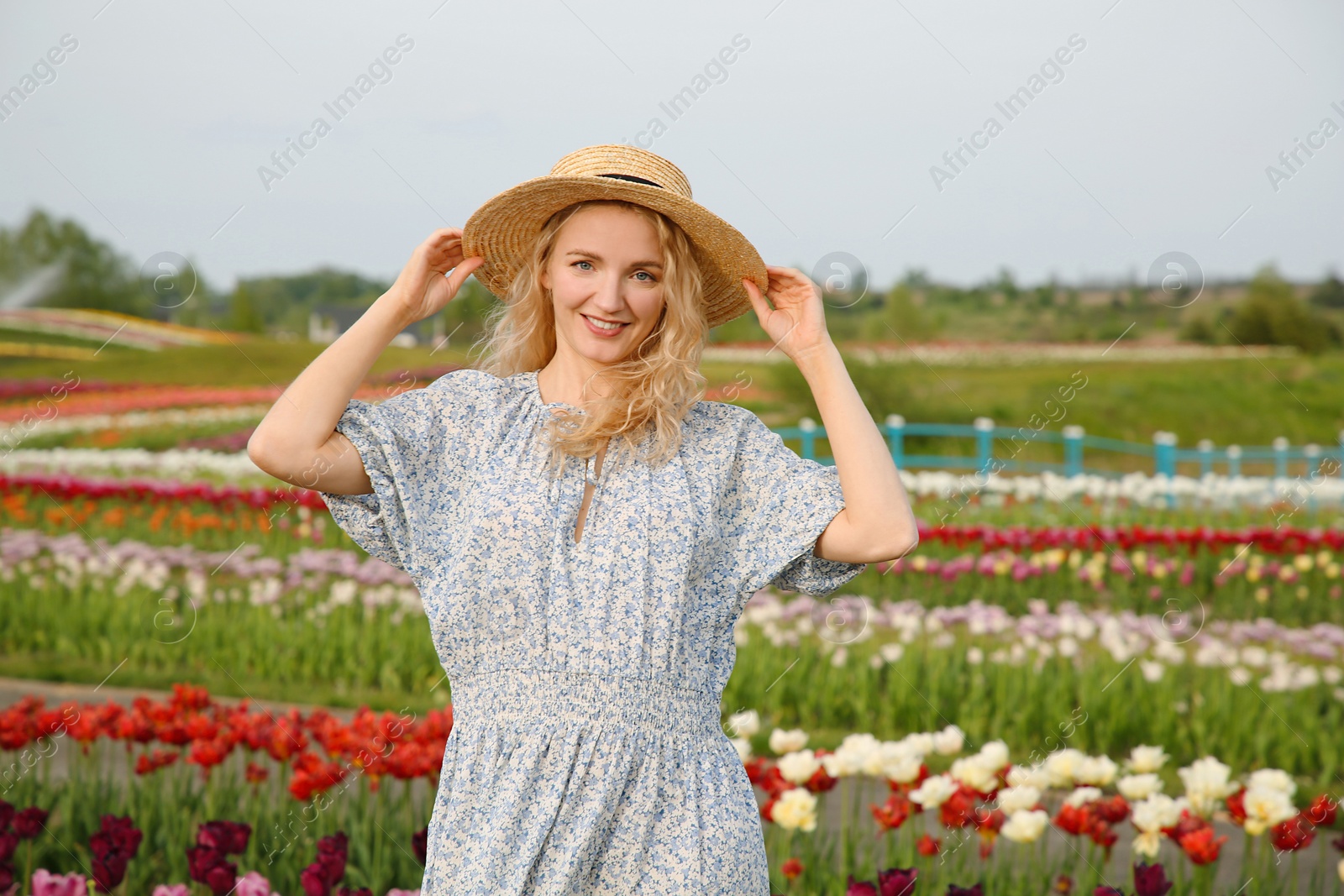 Photo of Happy woman in beautiful tulip field outdoors