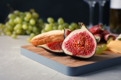 Photo of Wooden board with ripe fig slices on grey table, closeup