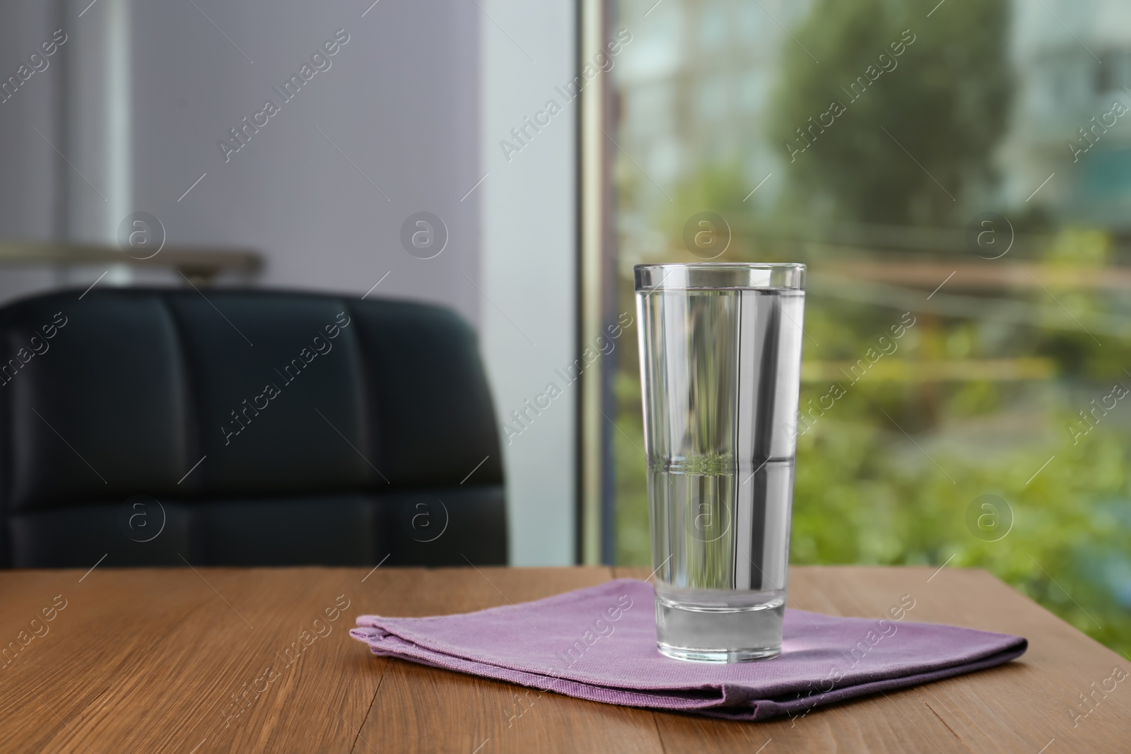 Photo of Glass of pure water on wooden table indoors, space for text