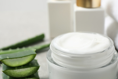 Open jar of cream and cut aloe on table, closeup. Organic cosmetics