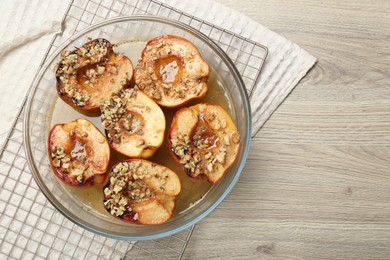 Photo of Delicious baked quinces with nuts and honey in bowl on wooden table, top view. Space for text