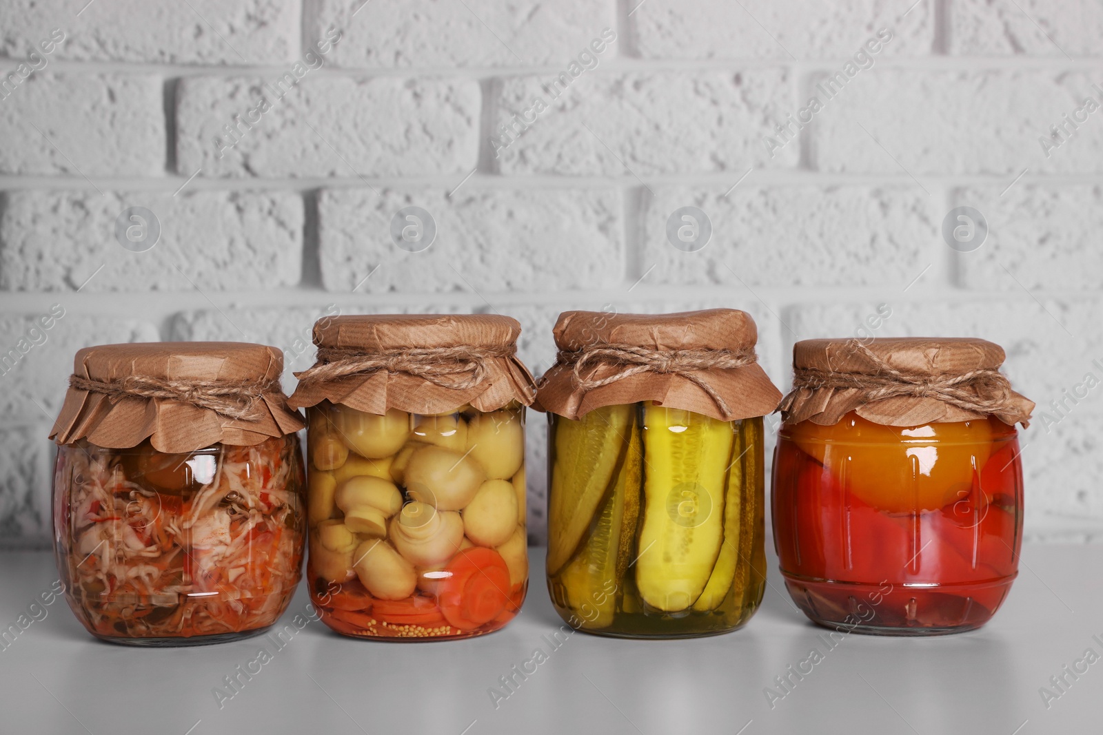 Photo of Many glass jars with different preserved vegetables and mushrooms on light grey table