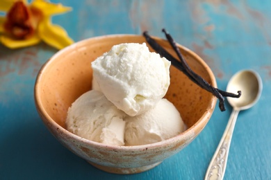 Photo of Bowl with tasty vanilla ice cream on wooden background