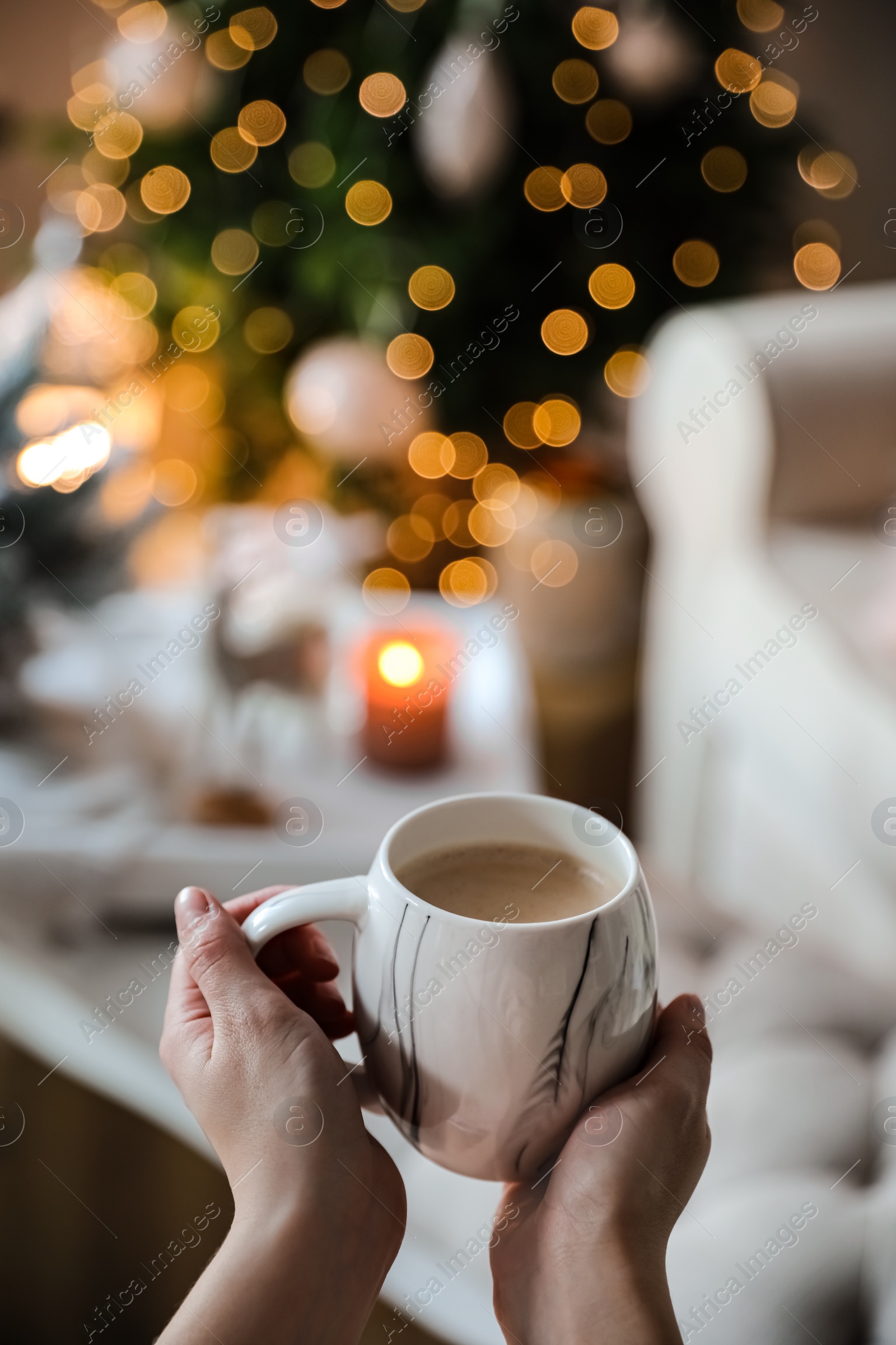 Photo of Woman with cup of cocoa in room decorated for Christmas, closeup