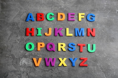 Photo of Colorful magnetic letters on grey stone background, flat lay. Alphabetical order