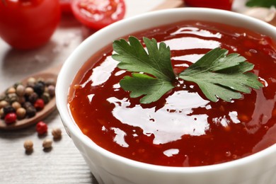 Photo of Spicy chili sauce with parsley in bowl on white table, closeup