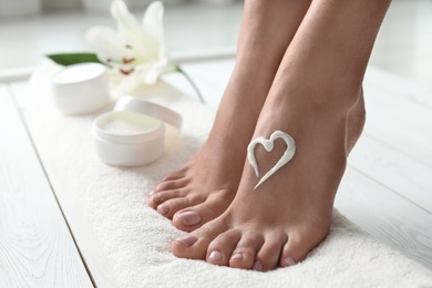 Photo of Woman with beautiful feet and cream on white towel, closeup. Spa treatment