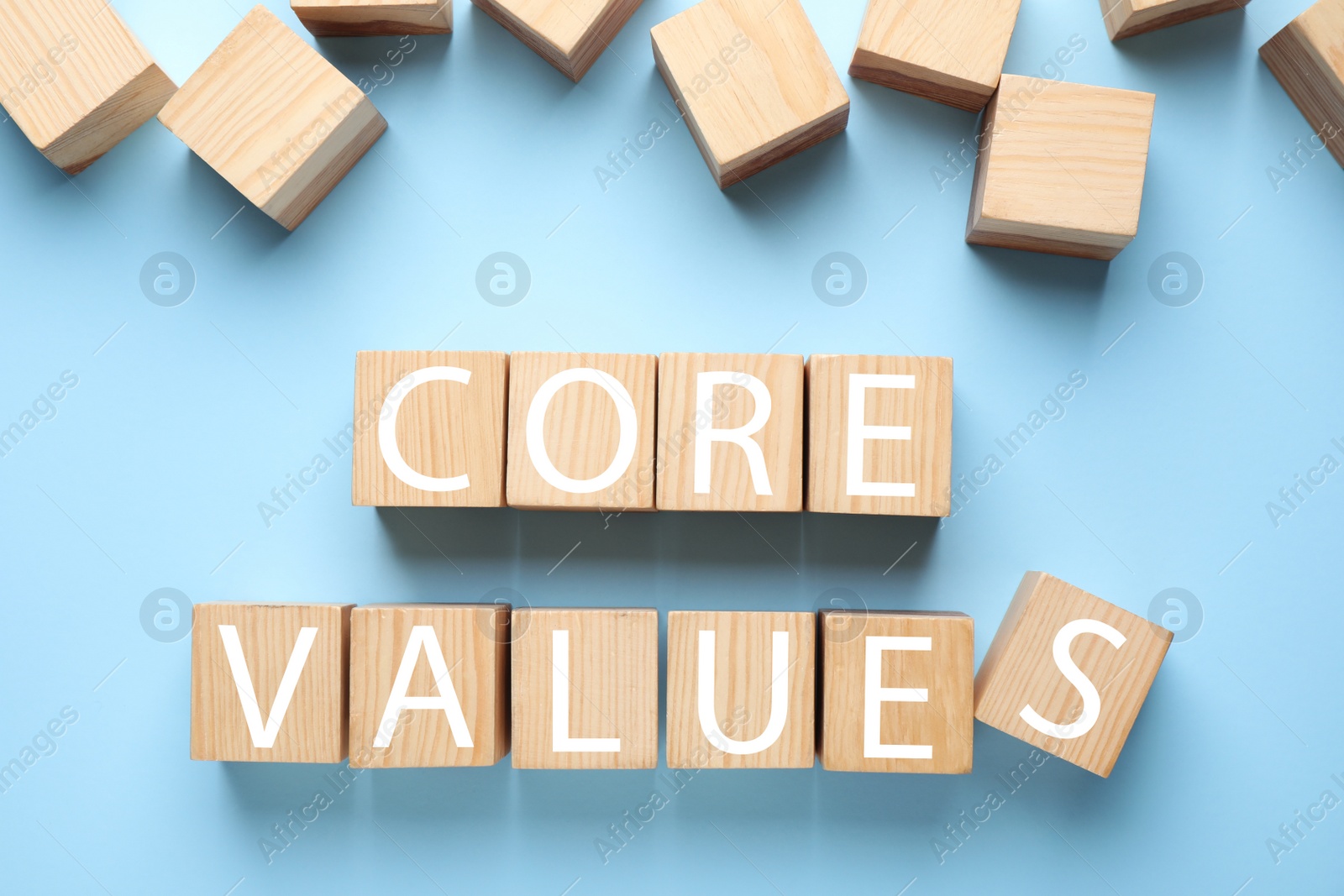 Photo of Wooden cubes with phrase CORE VALUES on light blue background, flat lay