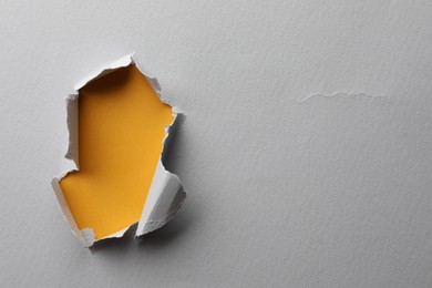 Hole in white paper on yellow background, space for text