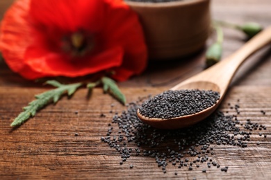 Photo of Composition with poppy seeds and flower on wooden table, space for text