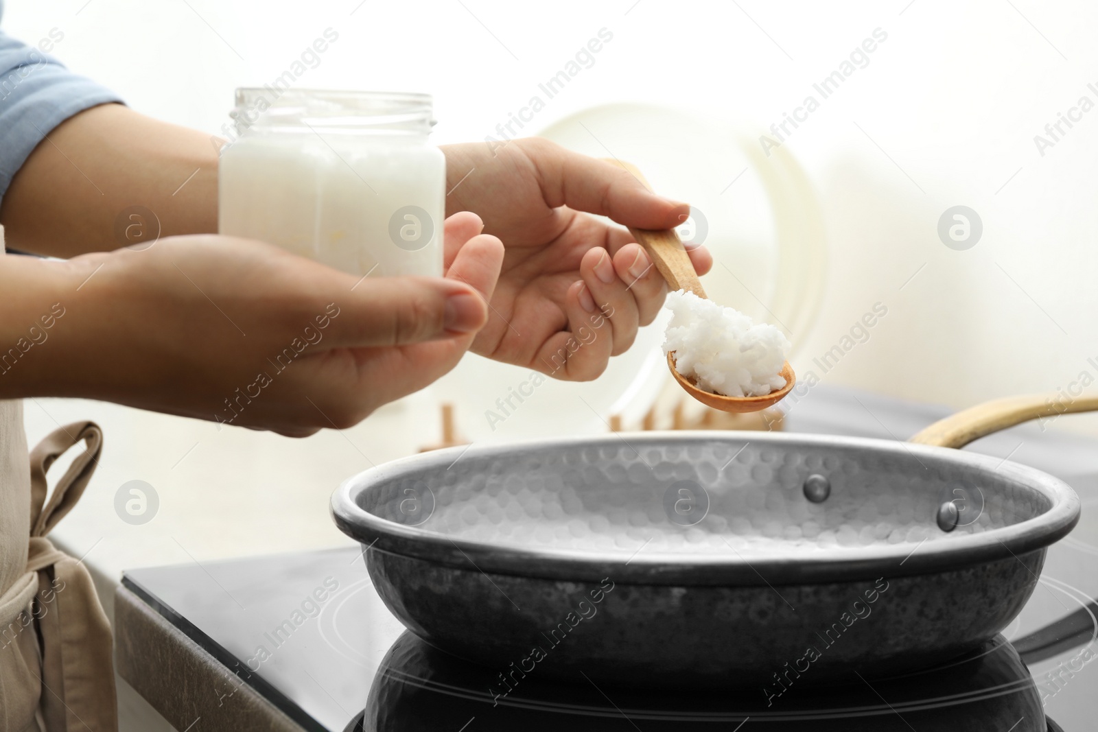 Photo of Woman cooking with coconut oil on induction stove, closeup