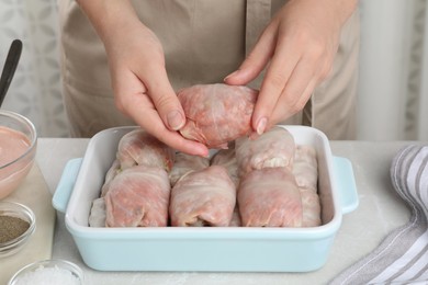 Photo of Woman making stuffed cabbage rolls at table, closeup