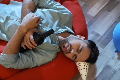 Photo of Young man sleeping in room after party, above view
