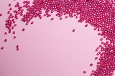Photo of Bright beads on pink background, flat lay. Space for text