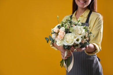 Photo of Florist with beautiful wedding bouquet on yellow background, closeup. Space for text