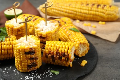 Photo of Tasty grilled corn on grey table, closeup