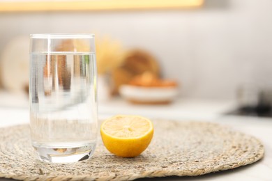 Photo of Glass with clear water and half of lemon on table in kitchen, space for text