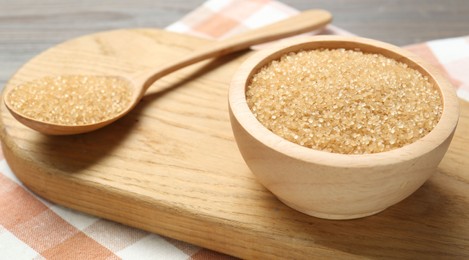 Photo of Brown sugar in bowl and spoon on table, closeup