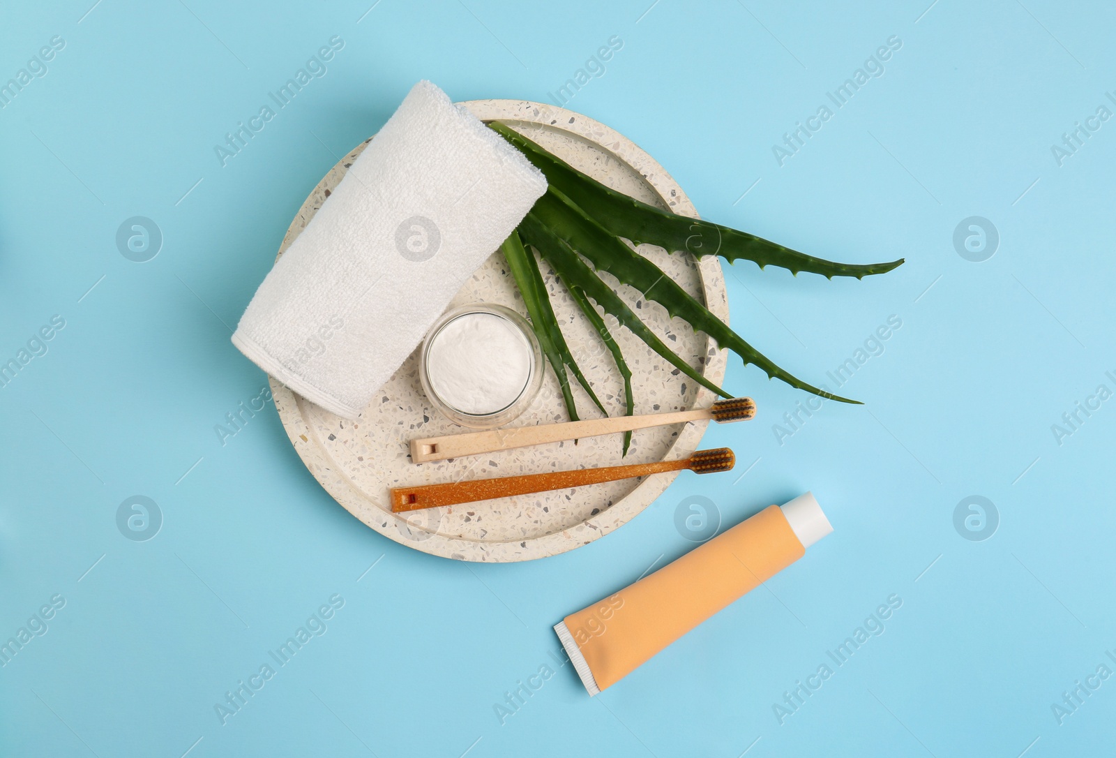 Photo of Tube of toothpaste, fresh aloe and care products on light blue background, flat lay