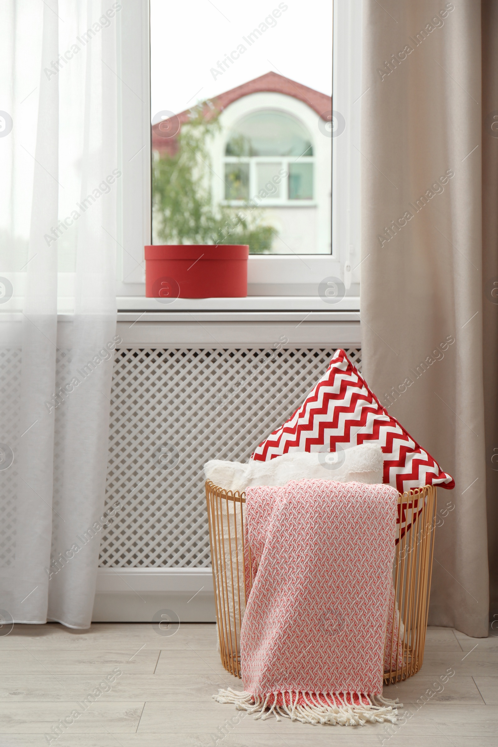 Photo of Basket with pillows and plaid near window in modern room