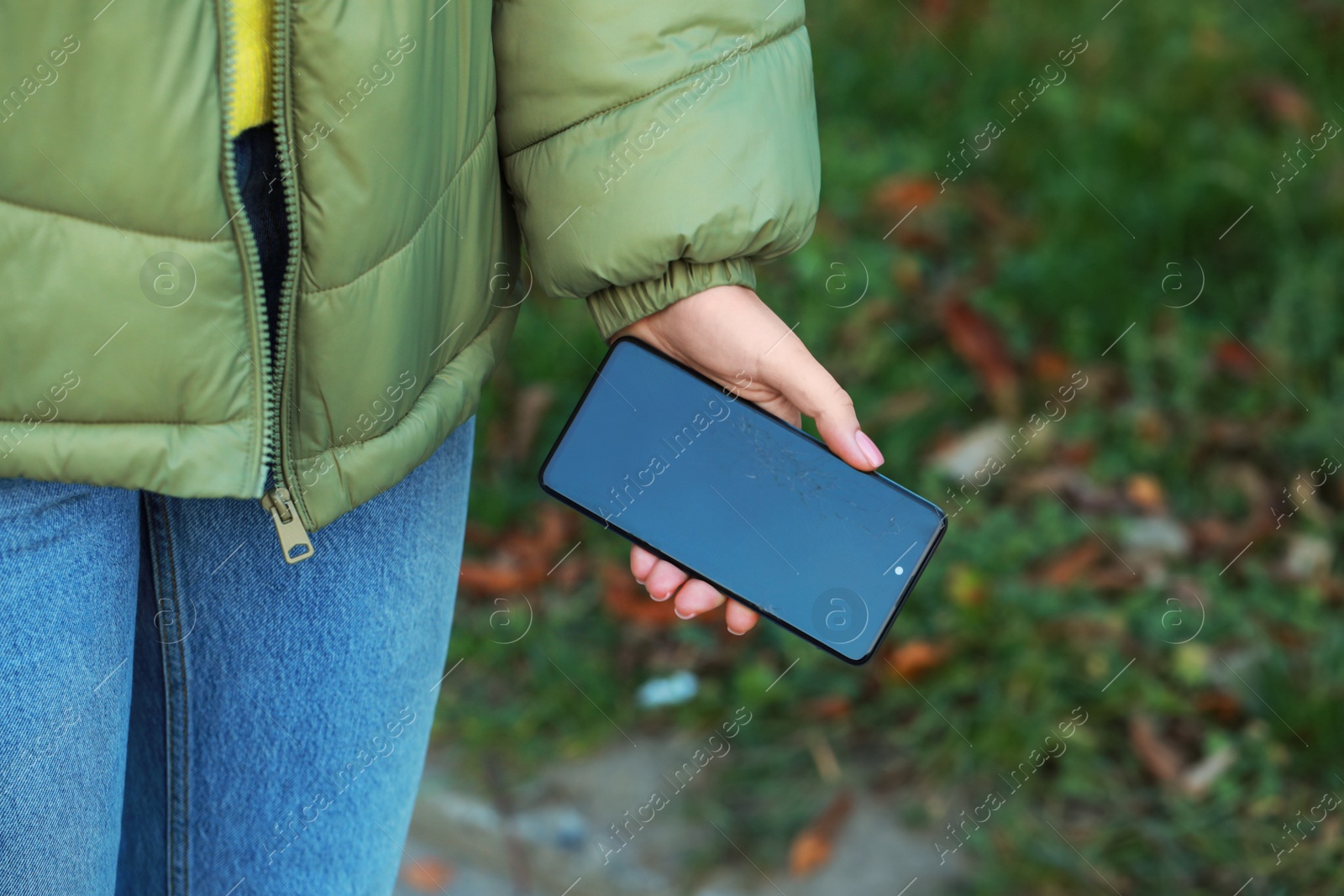 Photo of Woman holding damaged smartphone outdoors, closeup. Device repairing