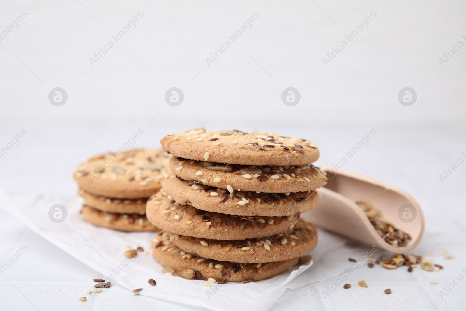 Photo of Cereal crackers with flax and sesame seeds on white tiled table, closeup