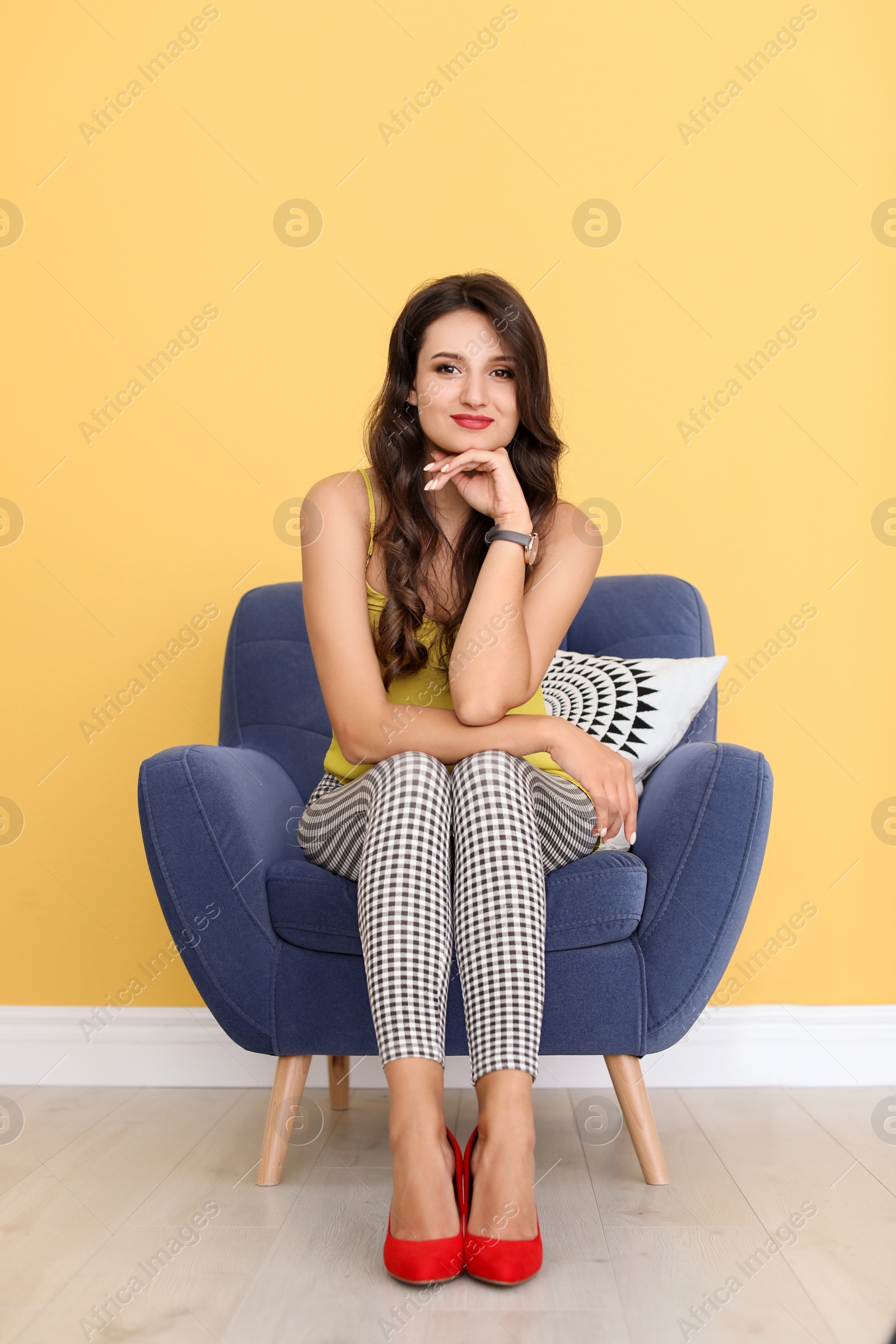 Photo of Beautiful young woman sitting in armchair wearing red elegant shoes