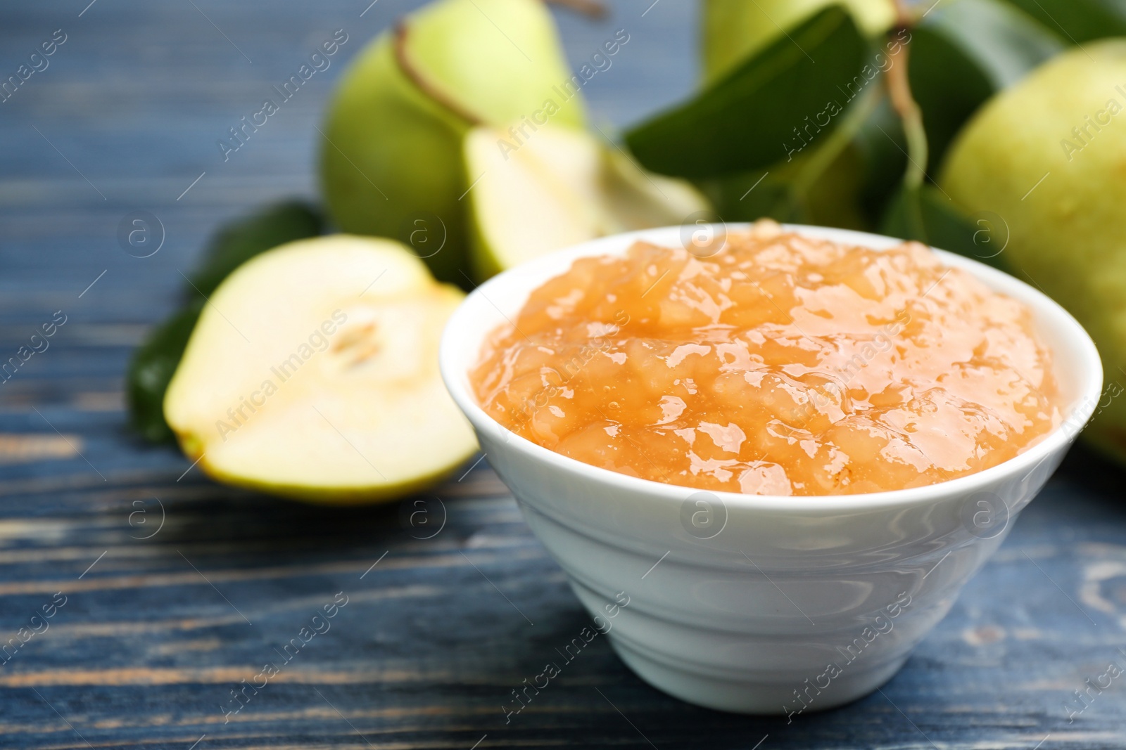 Photo of Tasty homemade pear jam and fresh fruits on blue wooden table