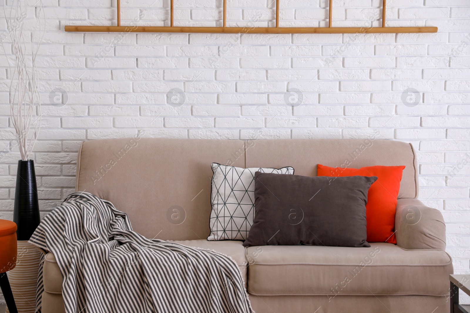 Photo of Soft pillows on sofa near white brick wall