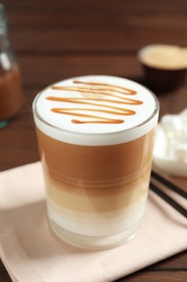 Photo of Glass with delicious caramel latte on table