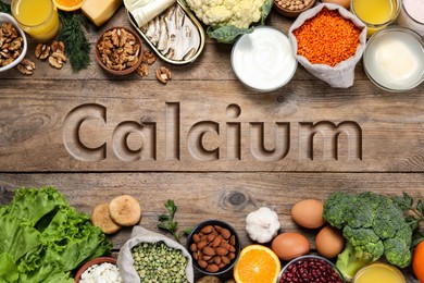 Different fresh products with high amounts of easily absorbable calcium on wooden table, flat lay