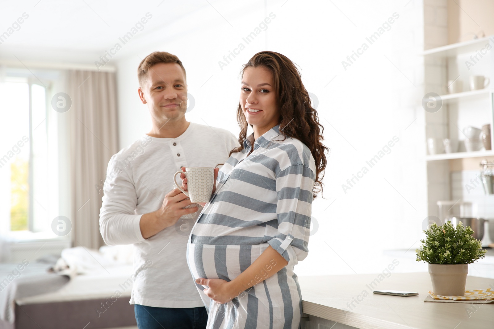 Photo of Pregnant woman with her husband in kitchen. Happy young family