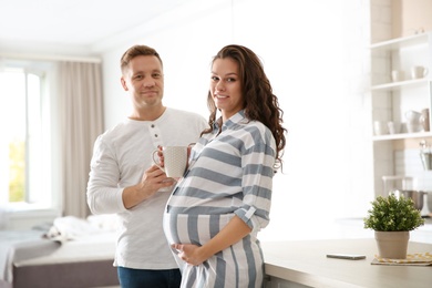 Pregnant woman with her husband in kitchen. Happy young family