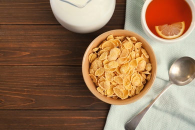 Photo of Flat lay composition with healthy cornflakes in bowl on wooden table. Space for text
