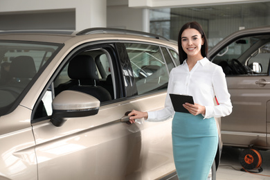 Saleswoman with clipboard near car in dealership