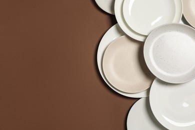 Photo of Different plates on brown background, flat lay. Space for text
